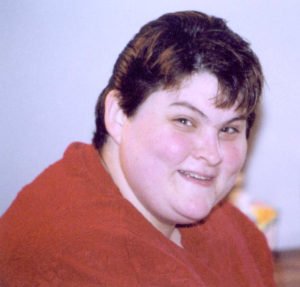 Photo: woman with short hair, wearing red shirt, smiling